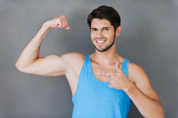 Cheerful muscular man pointing his bicep