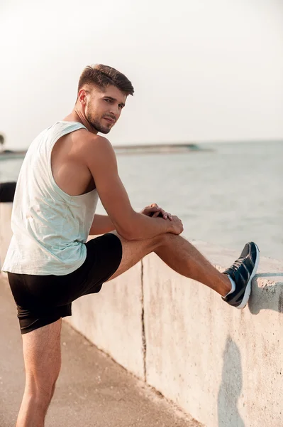 Muscular man stretching legs before running