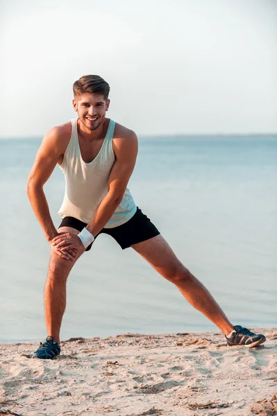 Muscular man stretching his legs