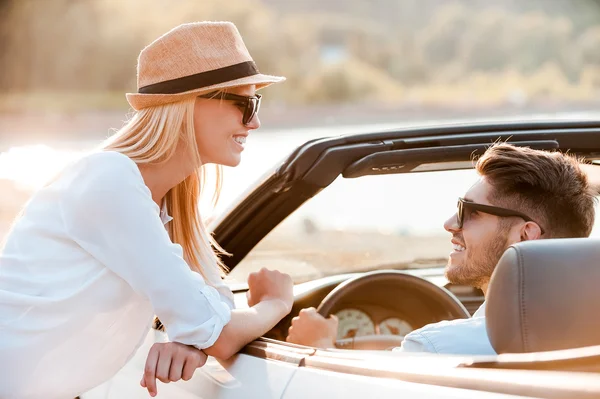 Man in convertible while his girlfriend leaning at  door