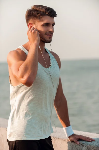 Muscular man in headphone leaning at parapet