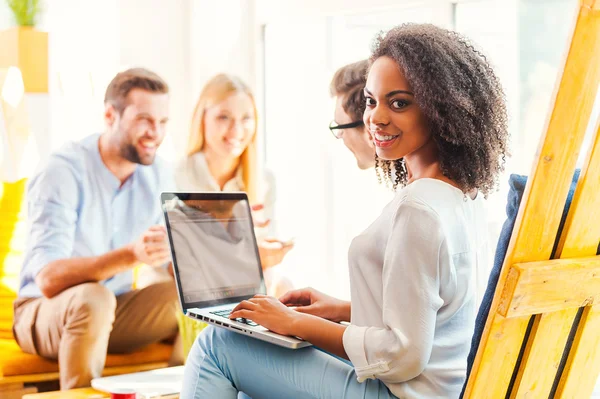 African woman working on laptop with colleagues