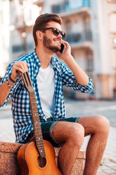 Man holding guitar and talking on phone
