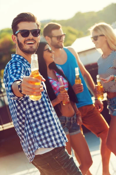 Young man stretching out bottle of beer