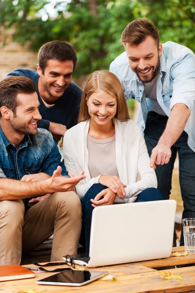 Cheerful young people looking at laptop