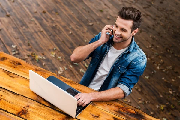 Man working on laptop and talking on phone