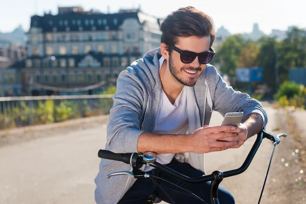 Man with bicycle and looking at his mobile phone