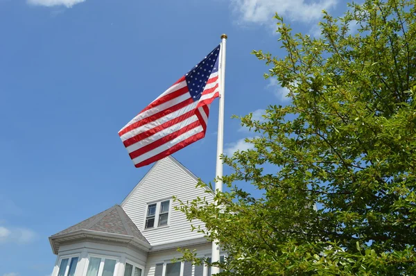 American flag with suburban home