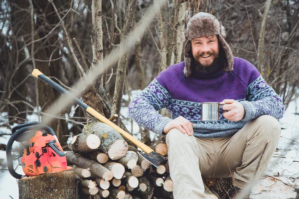 Bearded man drinking tea in the forest.Bearded woodcutter at rest in winter.