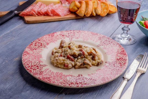 Risotto on a wood table with some antipasto in the background