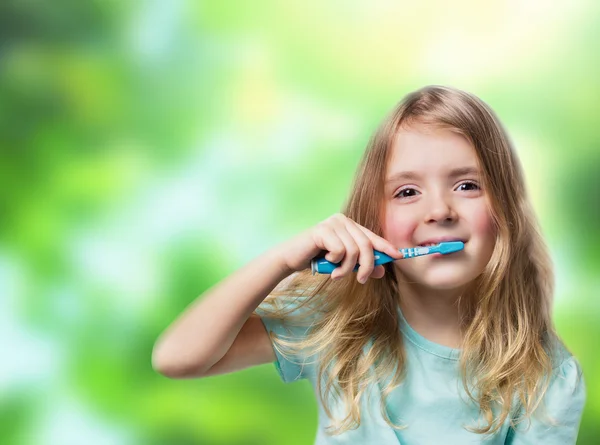Child girl with toothbrush on green nature background. Dental ba