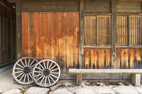 Old wooden house and Vintage wooden carriage wheel