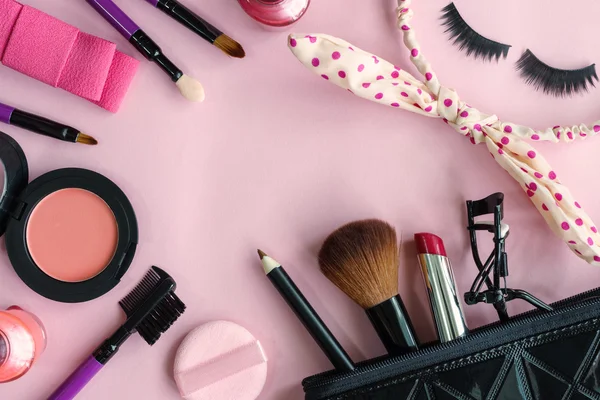 Various makeup products and cosmetics isolated on pink