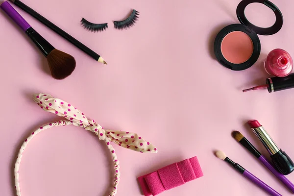 Various makeup products and cosmetics isolated on pink