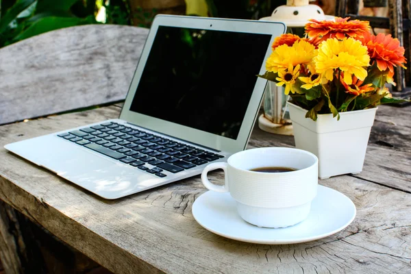 Coffee, laptop on wood floor with flower