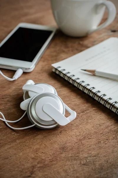 Earphone with coffee and notebook on old wooden table