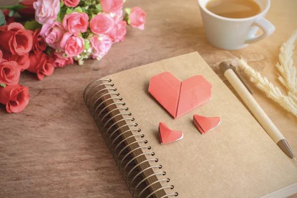 Cup of coffee with flower and red heart shape paper and notepad