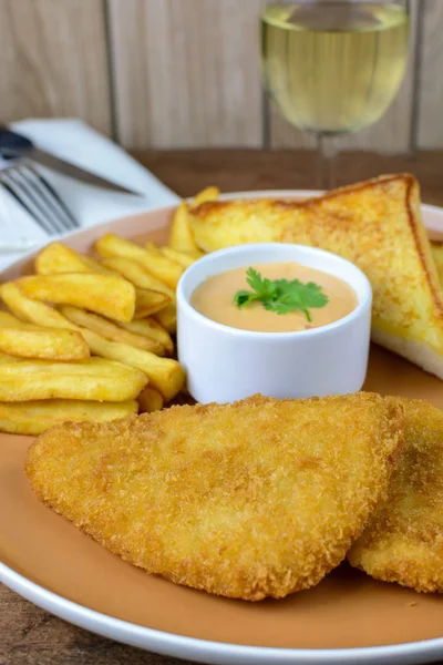 Crumbed fish and chips with glass of white wine