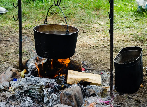Cooking in a hike in the cauldron hanging over the fire, from the boiler coming white smoke