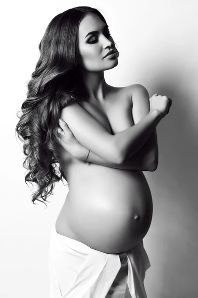 Beautiful pregnant woman with long dark hair, posing in studio