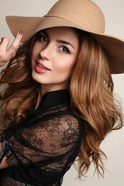Woman with dark hair wears elegant lace blouse and beige hat