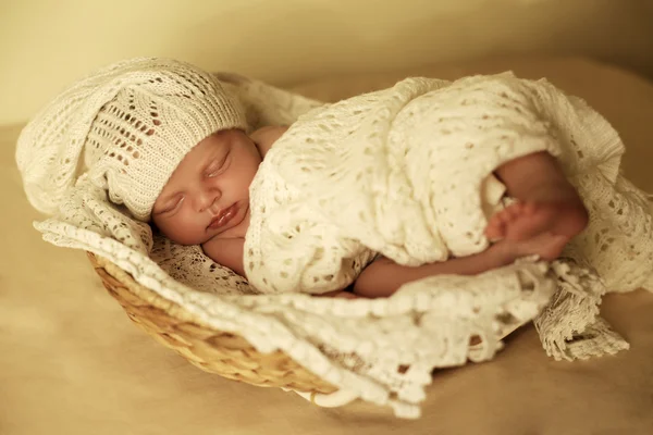 Newborn baby girl sleeping under cozy blanket in basket