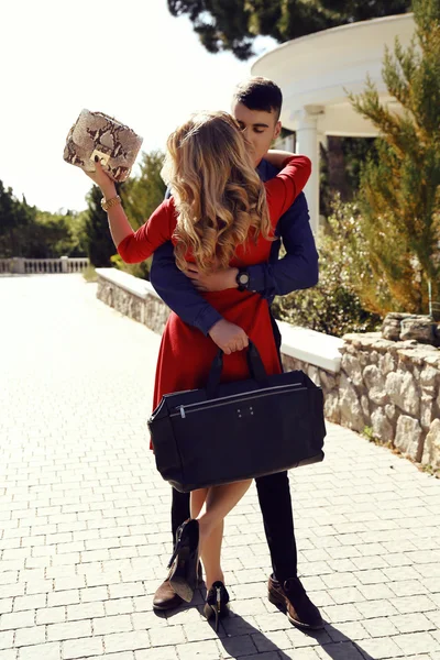 Beautiful couple in elegant clothes with bags posing in summer park