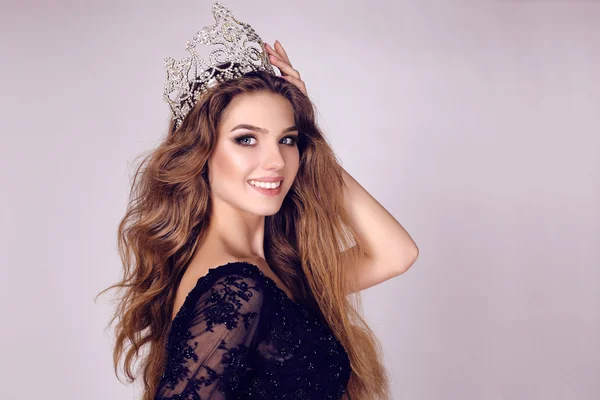 Gorgeous young woman with dark hair in luxurious dress with precious crown