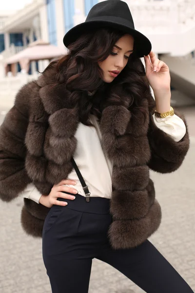 Woman with dark hair in elegant clothes and luxurious fur coat