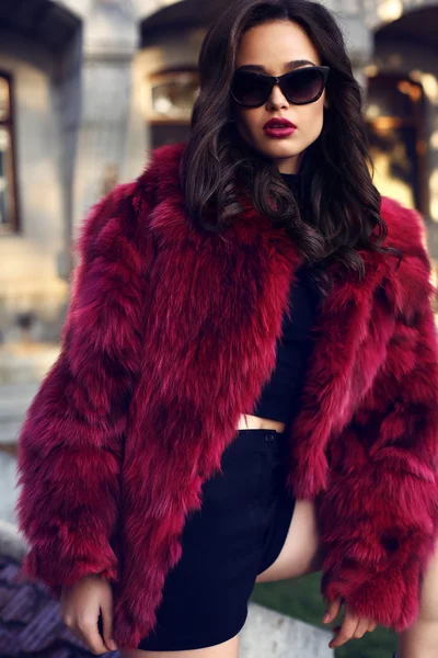 Sexy woman with dark hair in luxurious fur coat and sunglasses