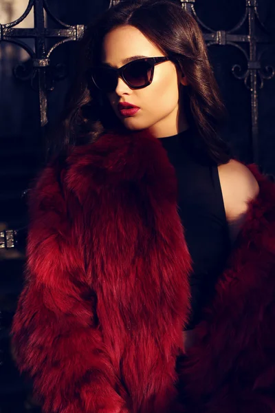 Portrait of sexy girl with dark hair in luxurious fur coat and sunglasses