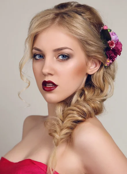 Sensual woman with blond curly hair with bright makeup and flower's hair accessory