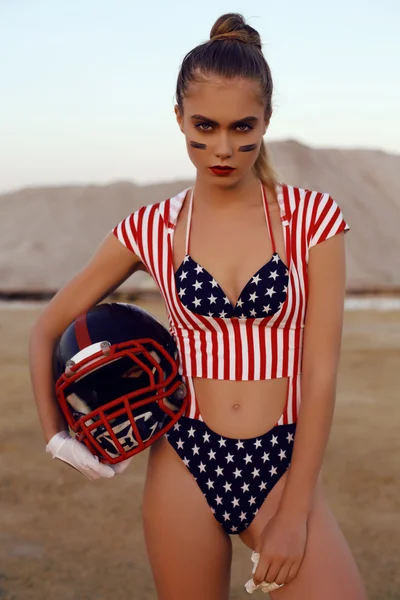 Sensual girl with blond hair looks like american football player