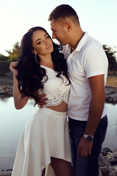 Beautiful sensual couple in elegant clothes posing in summer park