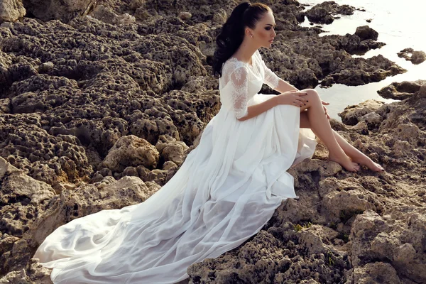 Young woman with long dark hair in luxurious lace wedding dress