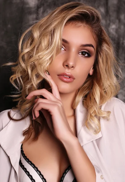 Beautiful woman with blond curly hair and evening makeup
