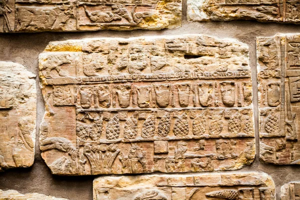 29. 07. 2015, LONDON, UK, BRITISH MUSEUM - Details from the Assyrian wall showing Egyptian buildings in the background. In the foreground, Nubian prisoners wear feather headdresses