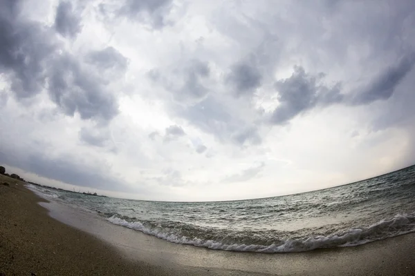 Aegean sea, beach and sky with clouds before the storm. Fish eye lens effect