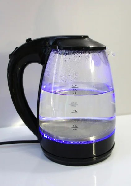 Glass electric kettle with water. Glass electric kettle with illuminated in the kitchen.