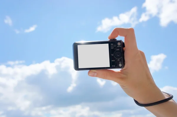 Hand holding digital camera. Girl\'s hand with the camera against the sky. Empty space for your picture or text.