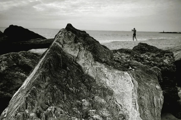 Rock, man, sky, ocean.