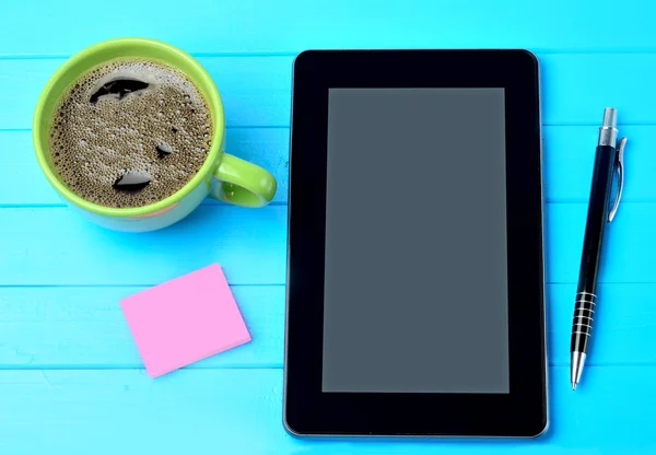 Tablet pc with coffee cup and notes on table