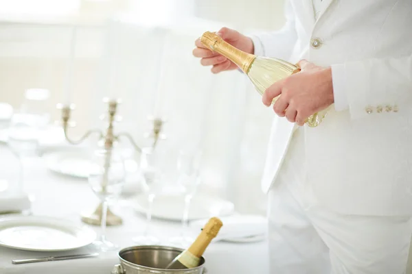 Man in white suit opens champagne