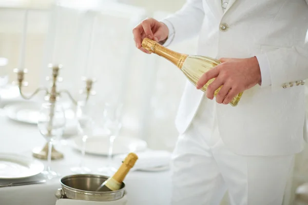 Man in white suit opens champagne