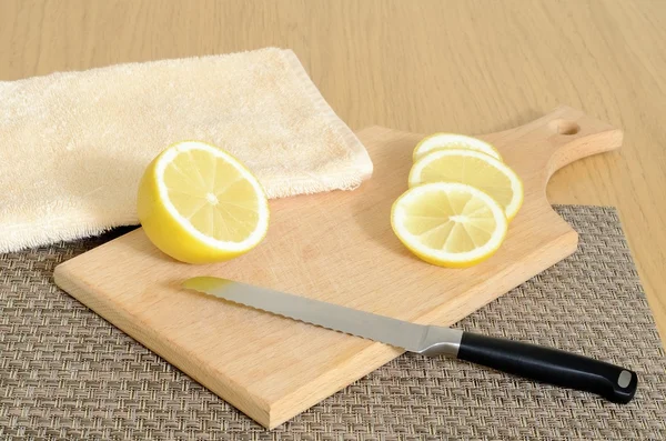 Kitchen culinary still life: sliced juicy lemon, a knife and cutting board on a wooden table