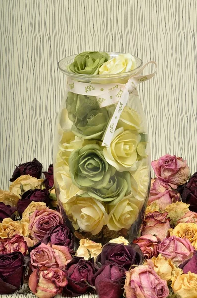 Transparent of glass vase with flowers roses and dried in the herbarium flowers in still life.