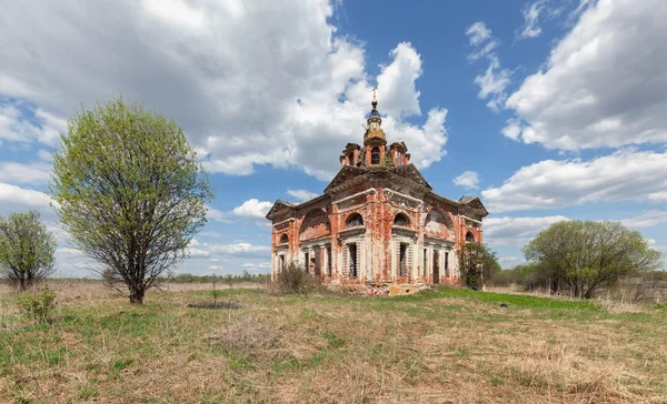 Abandoned old brick church in the countryside on the background of blue sky with clouds