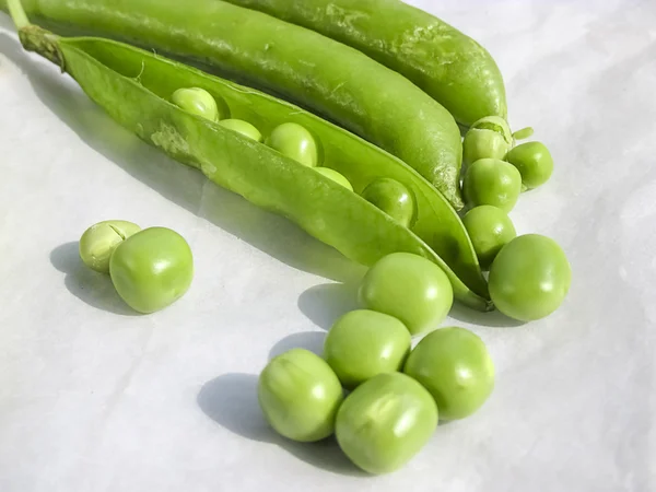 Green Peas and pea fruit the legume on white.