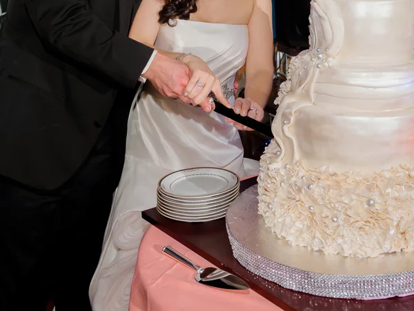 Close up of bride and groom cutting wedding cake