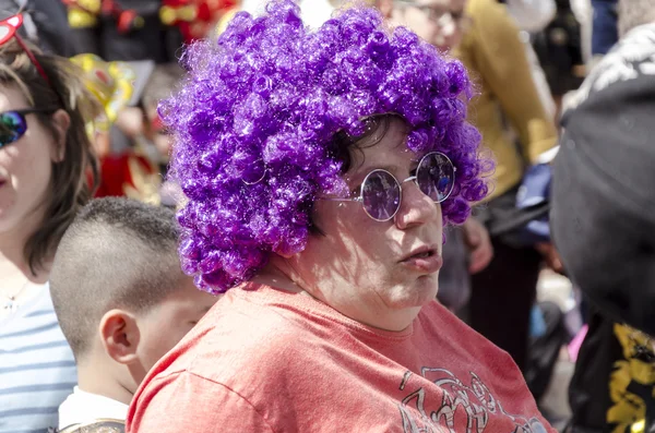 Beer-Sheva, ISRAEL - March 5, 2015: Curly woman in purple wig and sunglasses with round lenses in the crowd - Purim